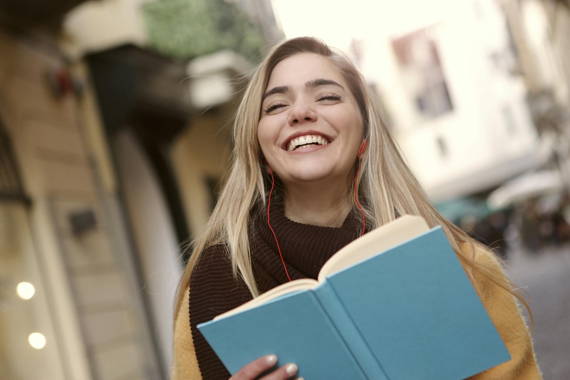 smiling woman in black and yellow long sleeve shirt holding blue book