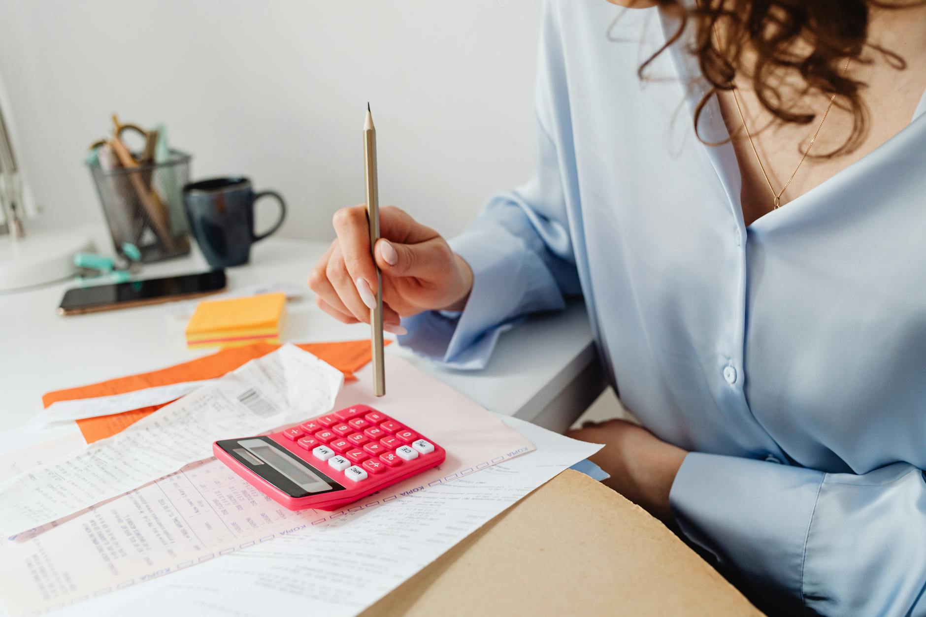 a woman computing bills while holding a pencil