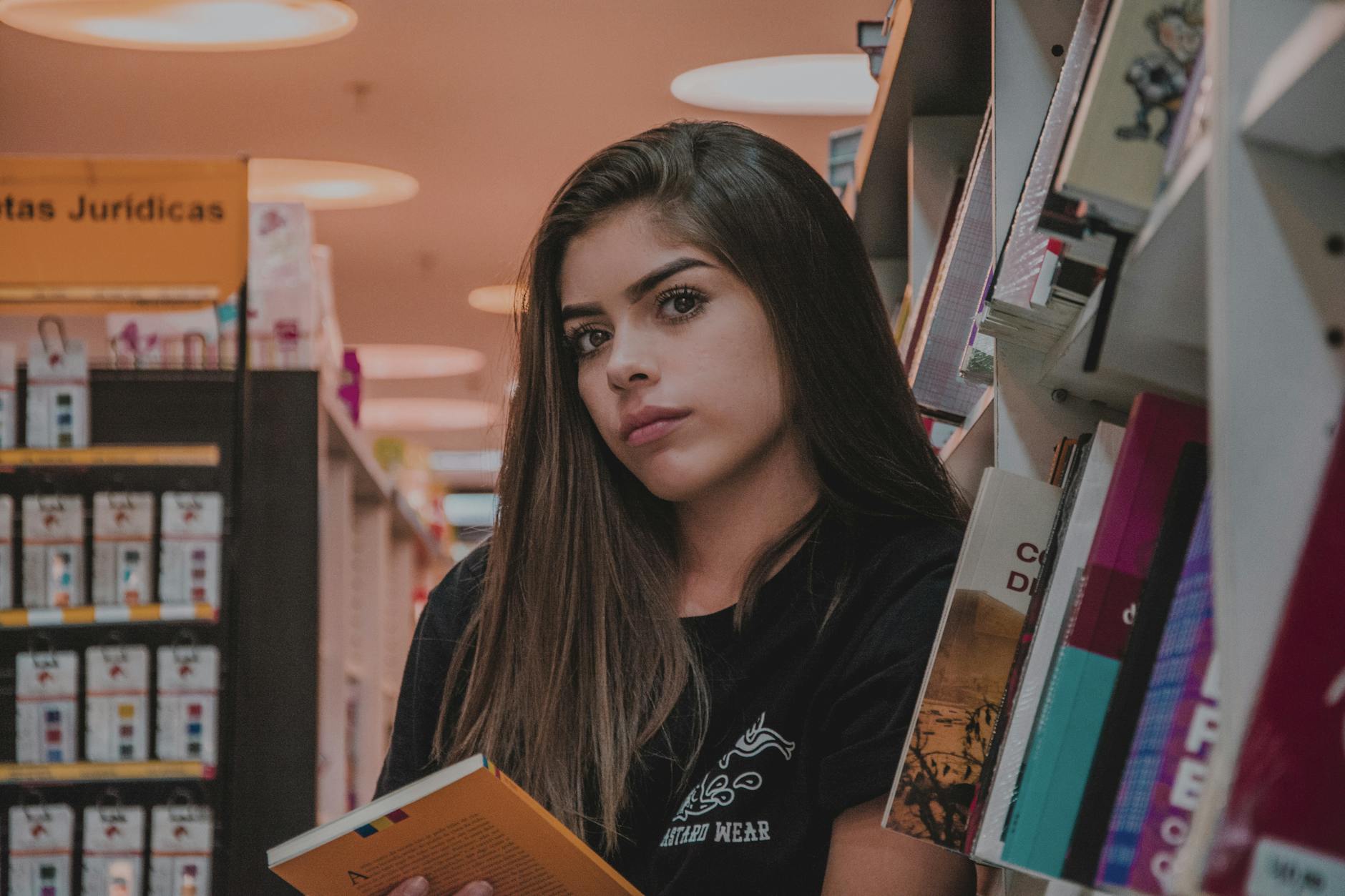 woman in black top leaning by bookcase