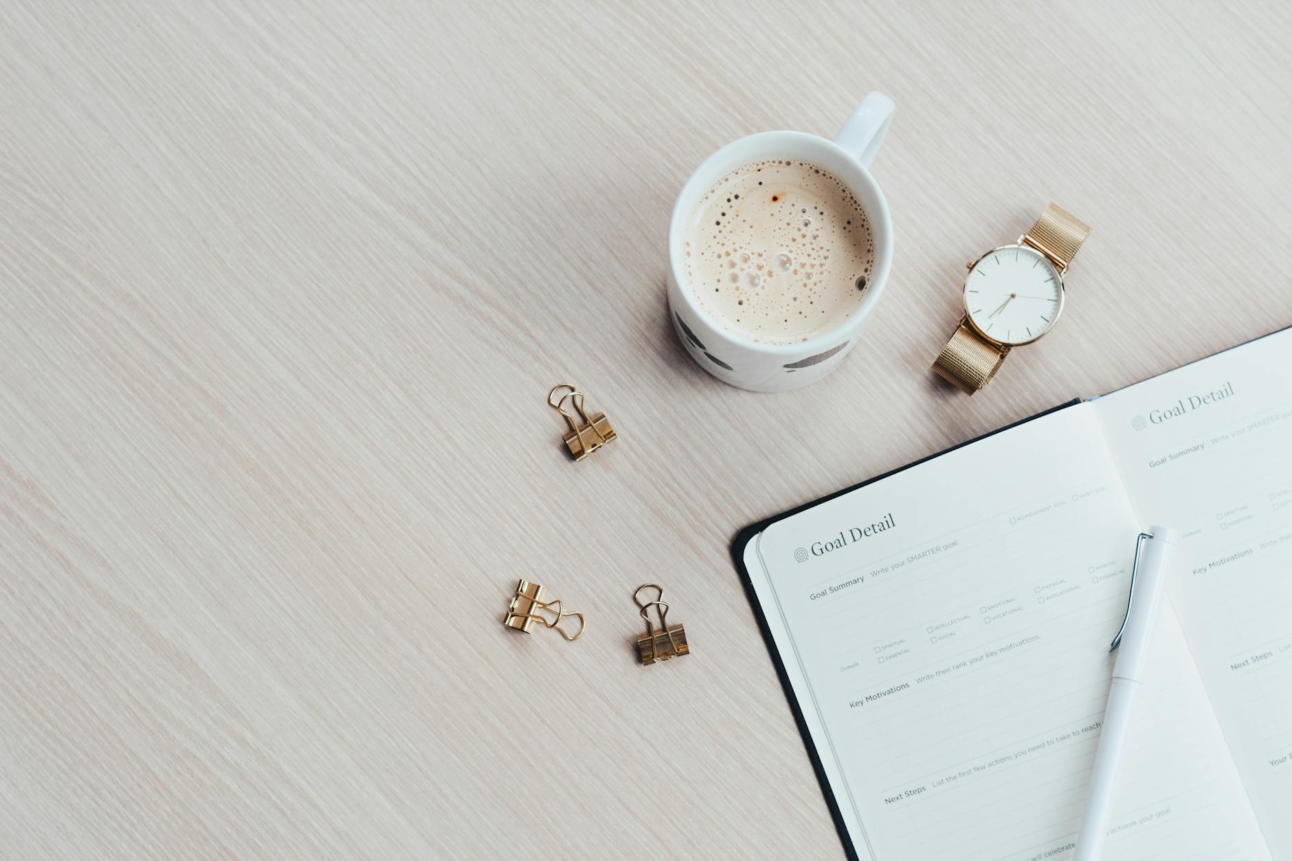 mug watch and planner book on brown wooden surface