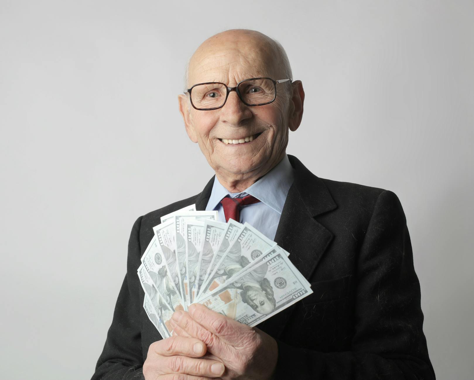 man in black suit holding dollar bills