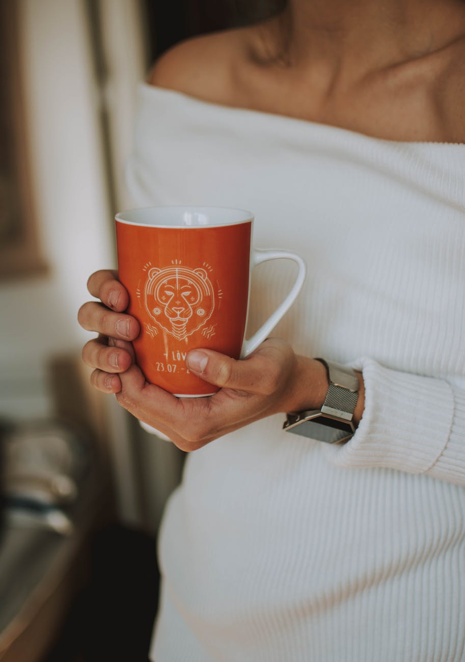 woman holding white and orange ceramic mug