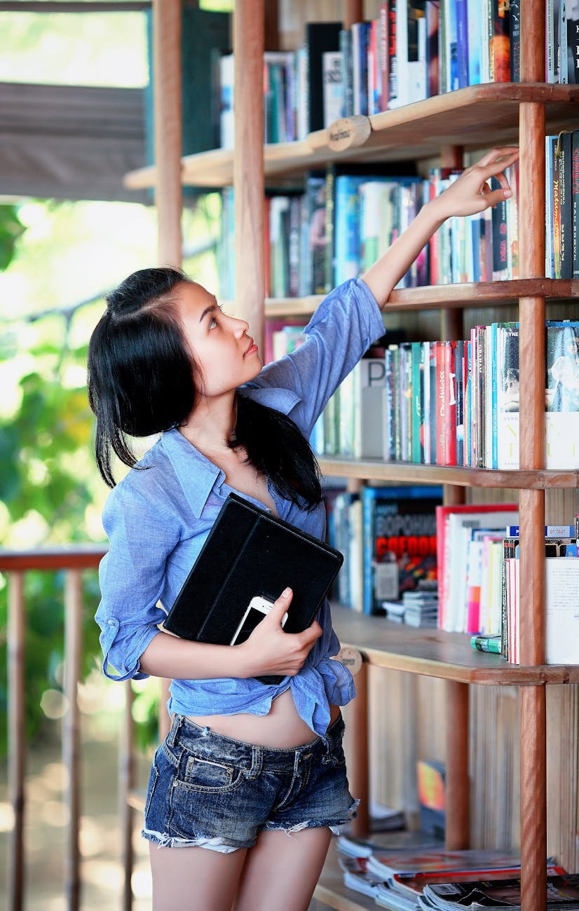 woman reaching book near handrail