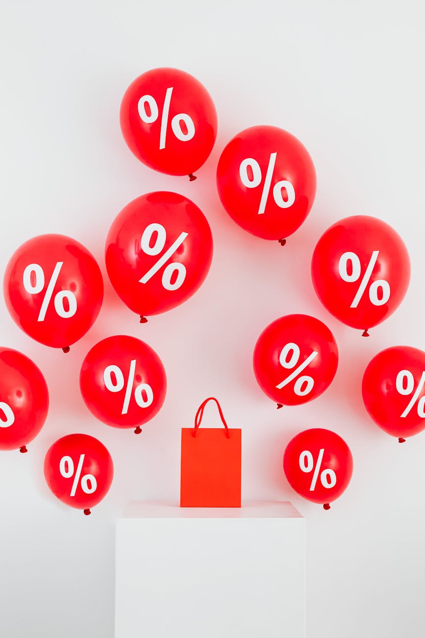 a red paper bag in the middle of red balloons with percentage symbols