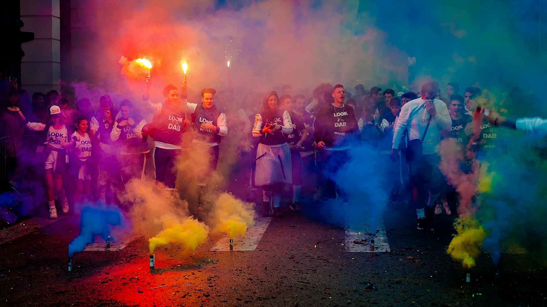 group of people on road with assorted color smokes