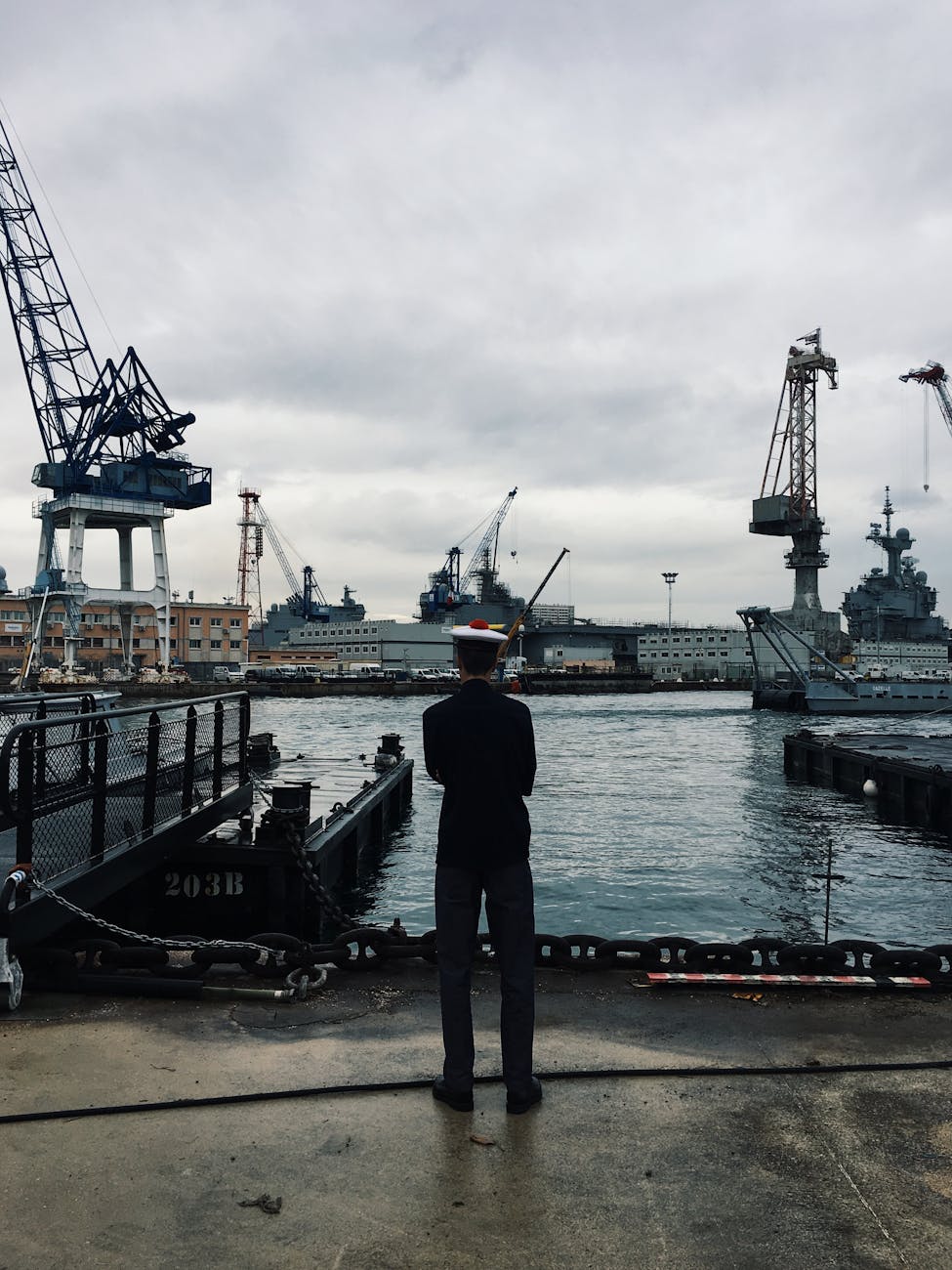 man standing and facing boats on water