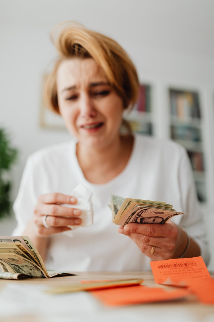 woman counting money and paying bills with sadness