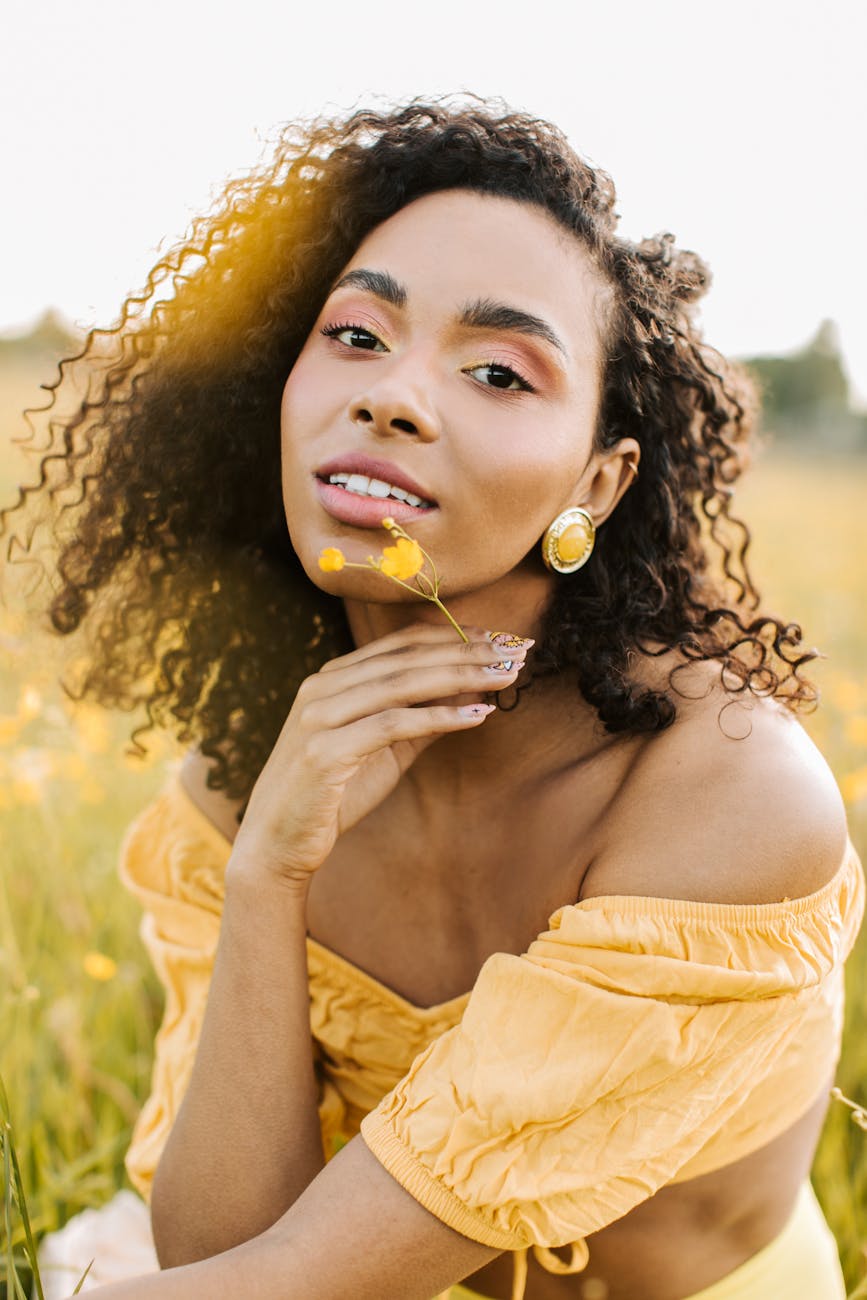 woman in off shoulder crop top holding yellow flower