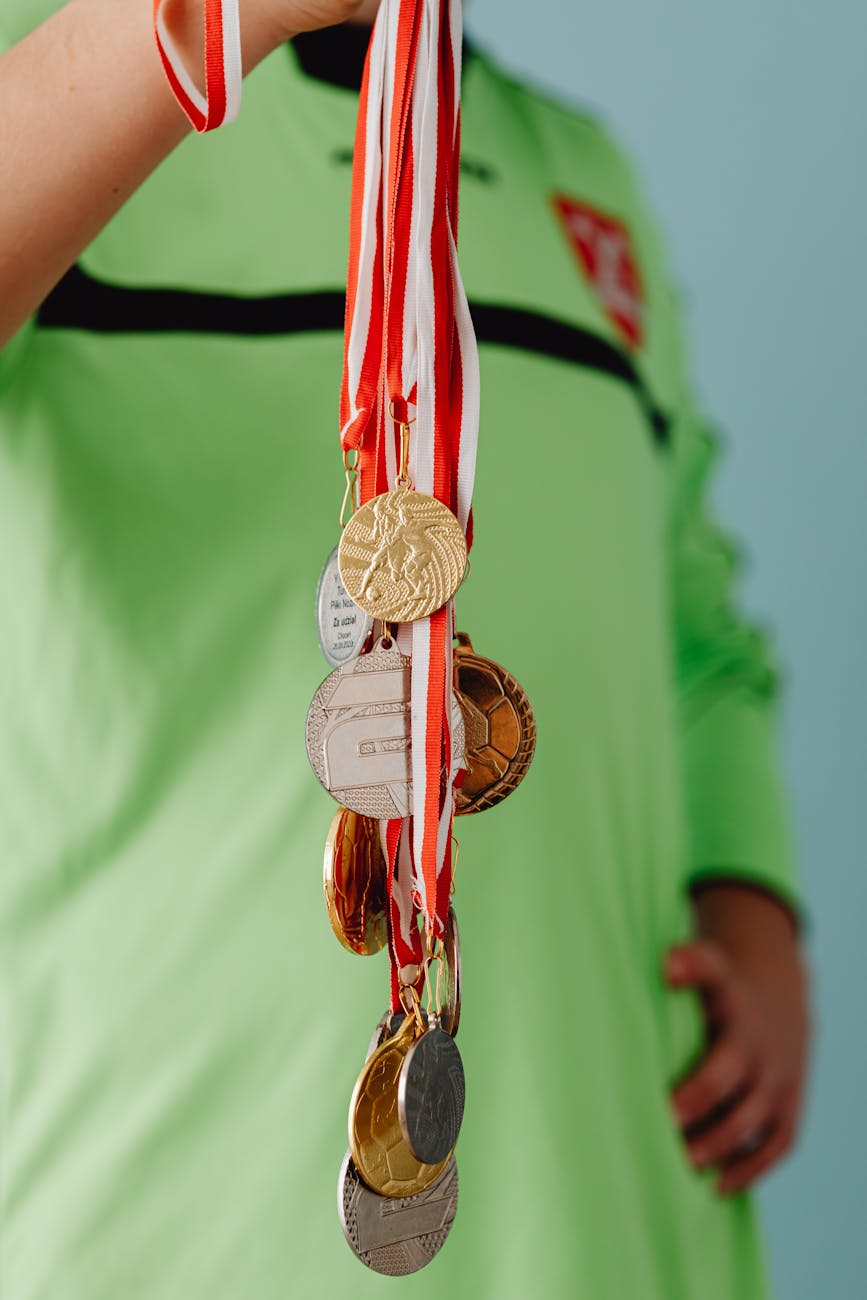 close up of a boy holding a bunch of medals