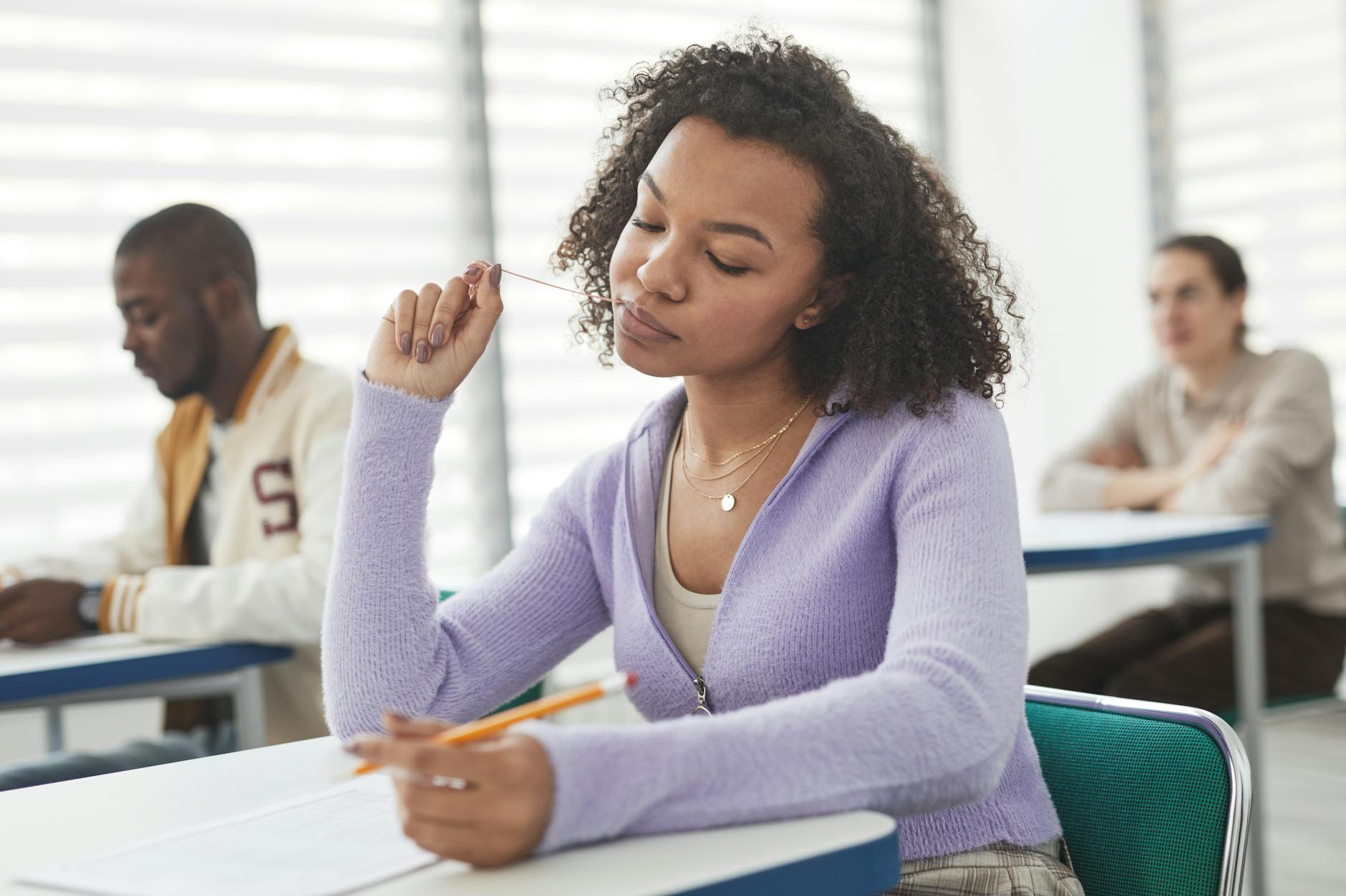 close up photo of a woman in a purple cardigan sweater taking an exam