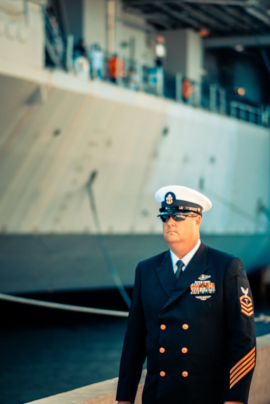 portrait of a us navy officer with a ship docked in the background