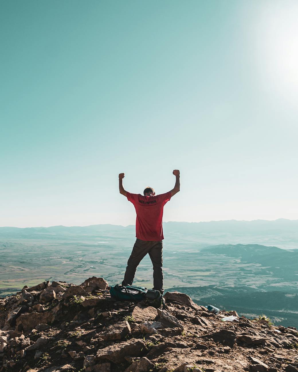 man in red shirt standing on rock formation