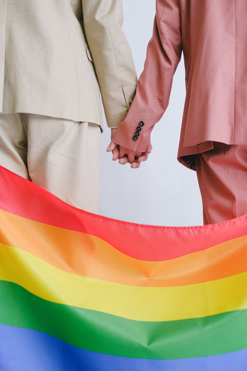 couple holding hands behind a gay pride flag
