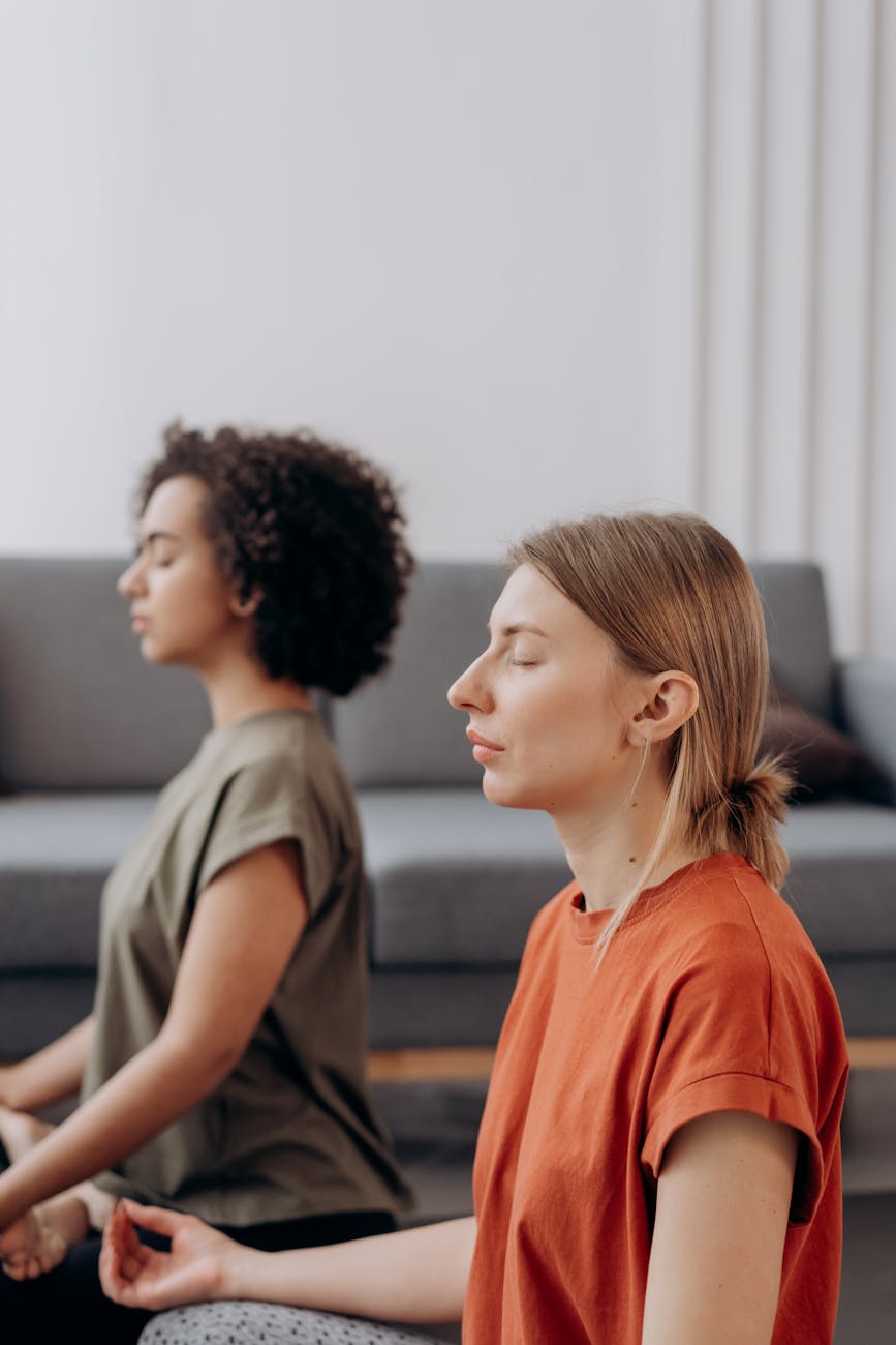 woman in orange shirt sitting beside woman in gray shirt