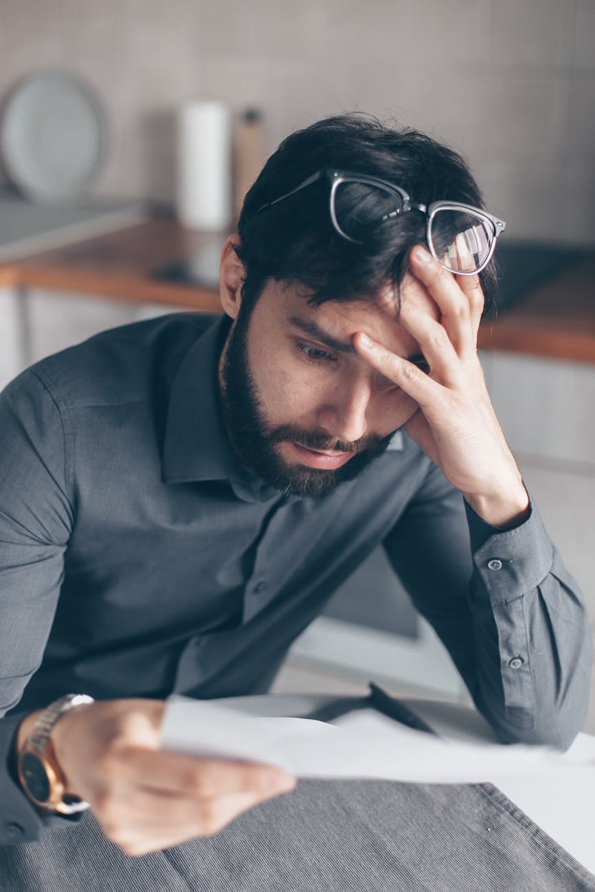 man in blue dress shirt with black framed eyeglasses feeling confused