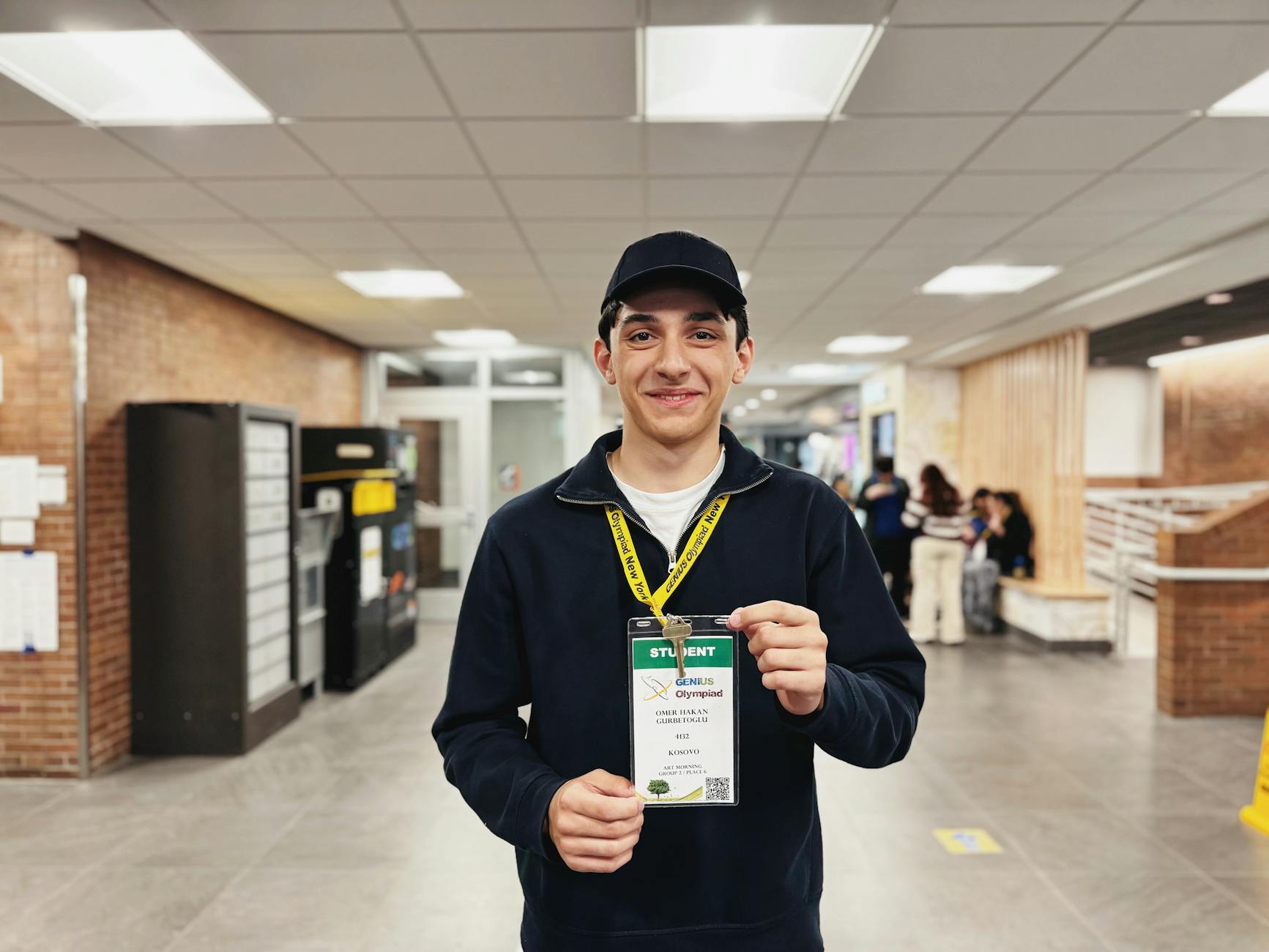 a young man with a student badge standing in the hallway