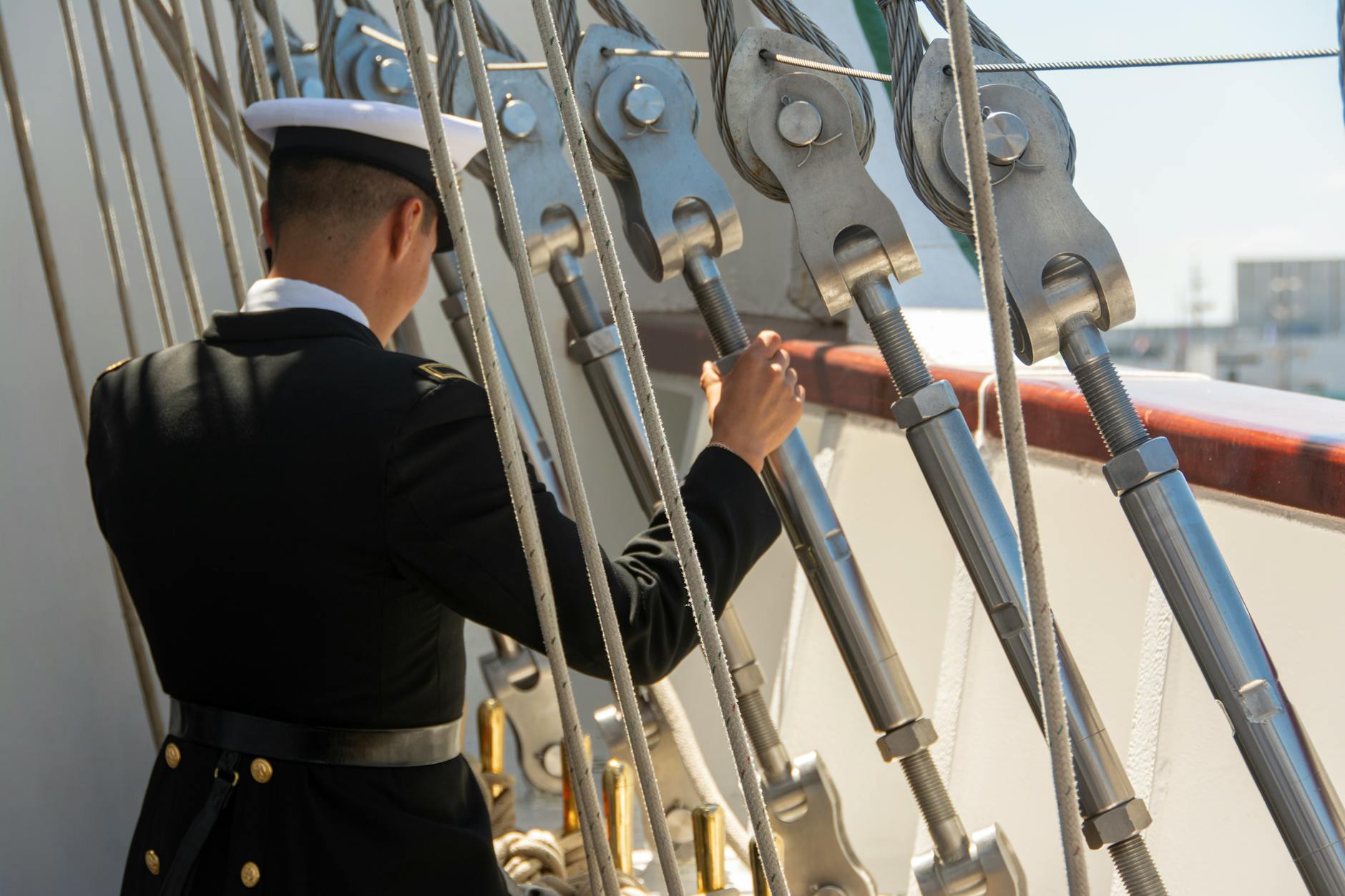 sailor adjusting ropes on ship deck