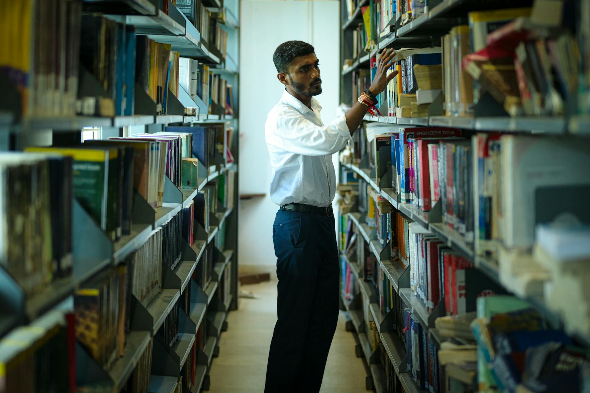 male student searching books in university library
