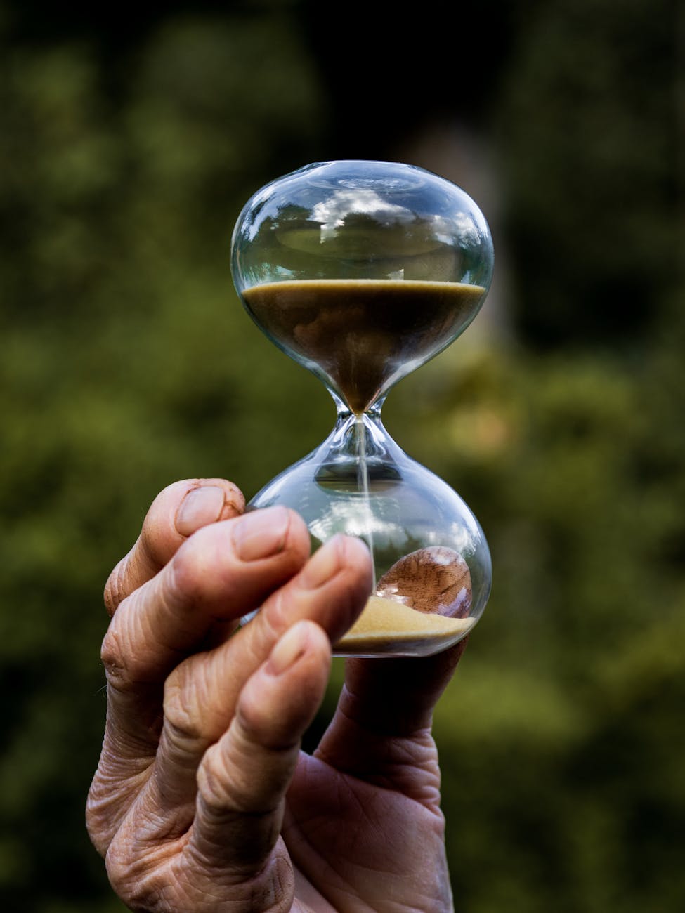 hand holding an hourglass against nature background