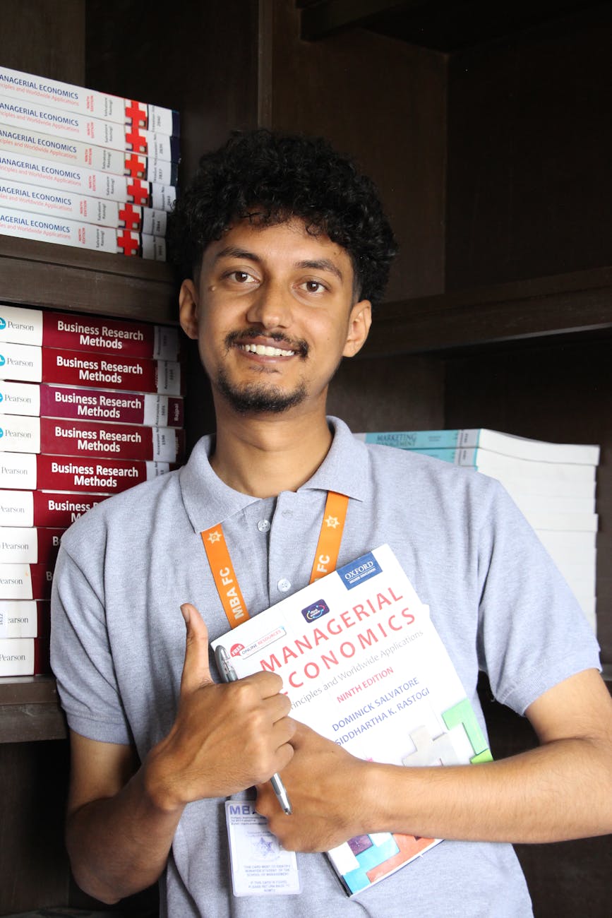 young student holding management textbook in library