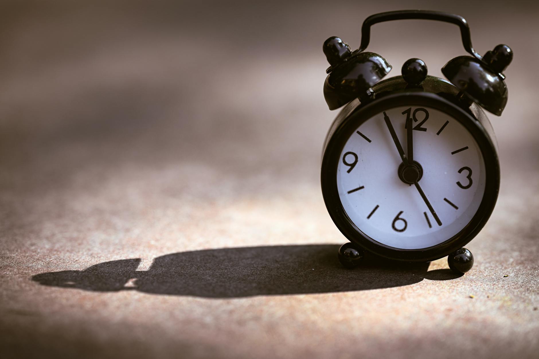 vintage alarm clock casting long shadow