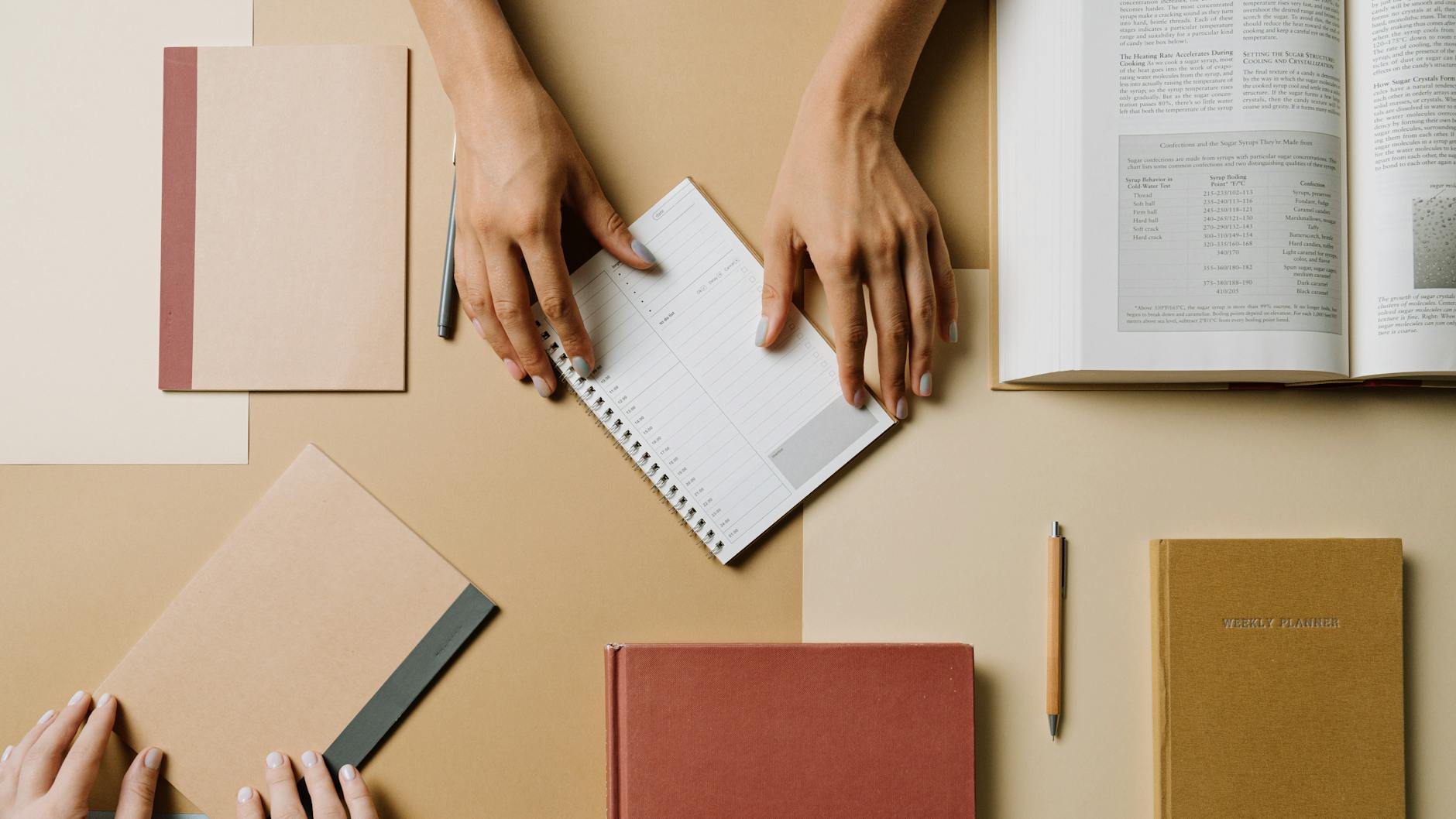 top view of hands touching notebooks on brown background