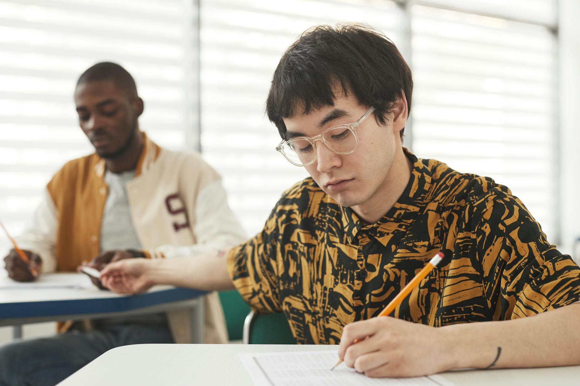 a man handing over a cheat sheet on his classmate