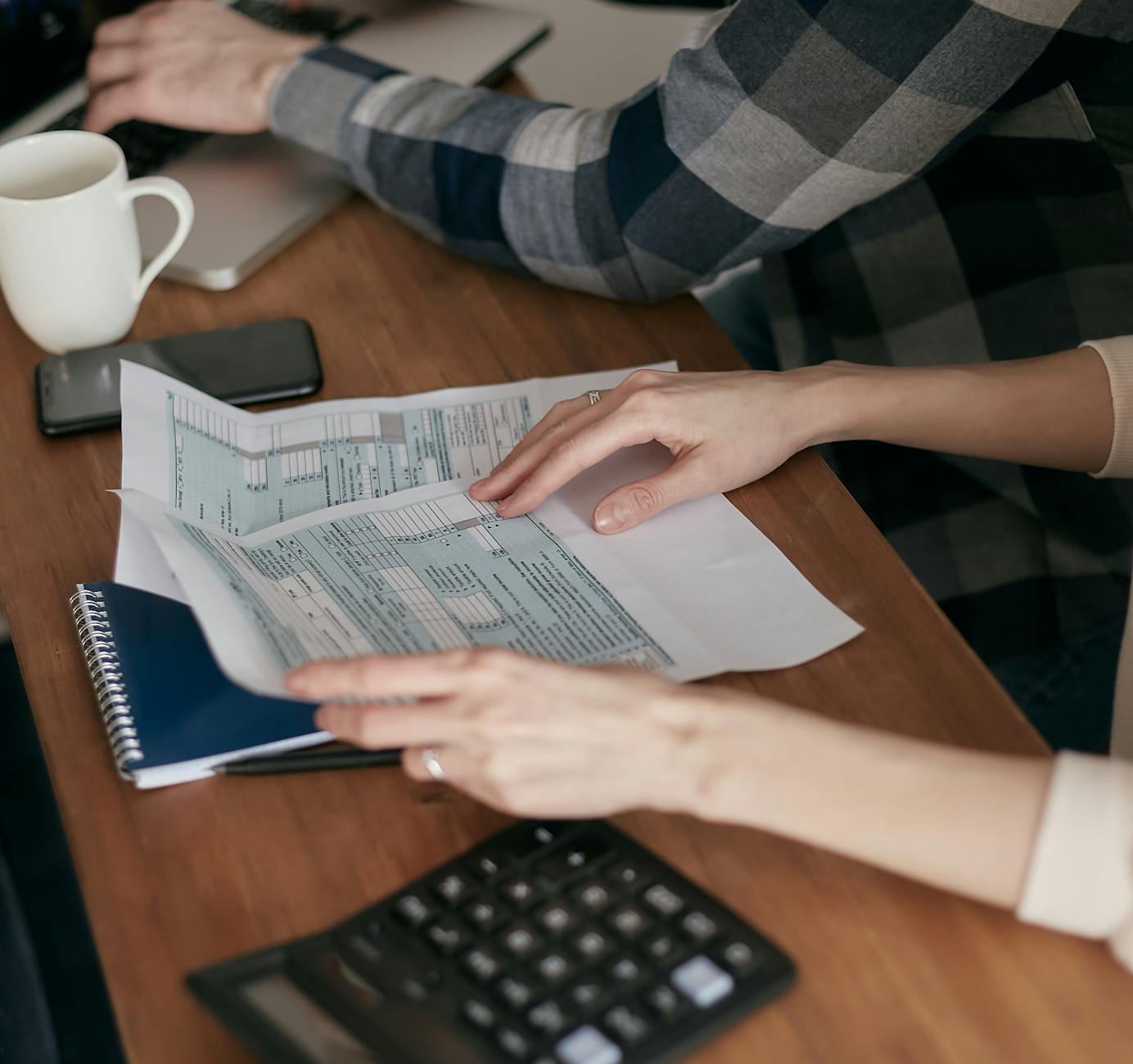 a person holding tax forms on wooden table