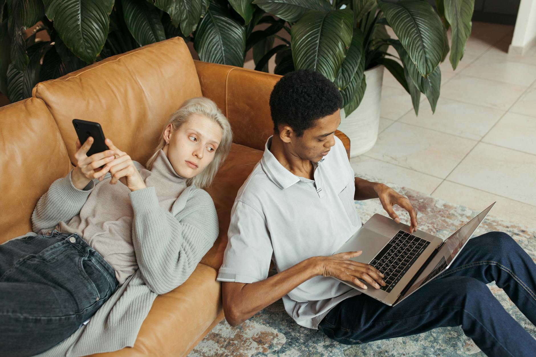 a man typing on laptop while sitting on the floor