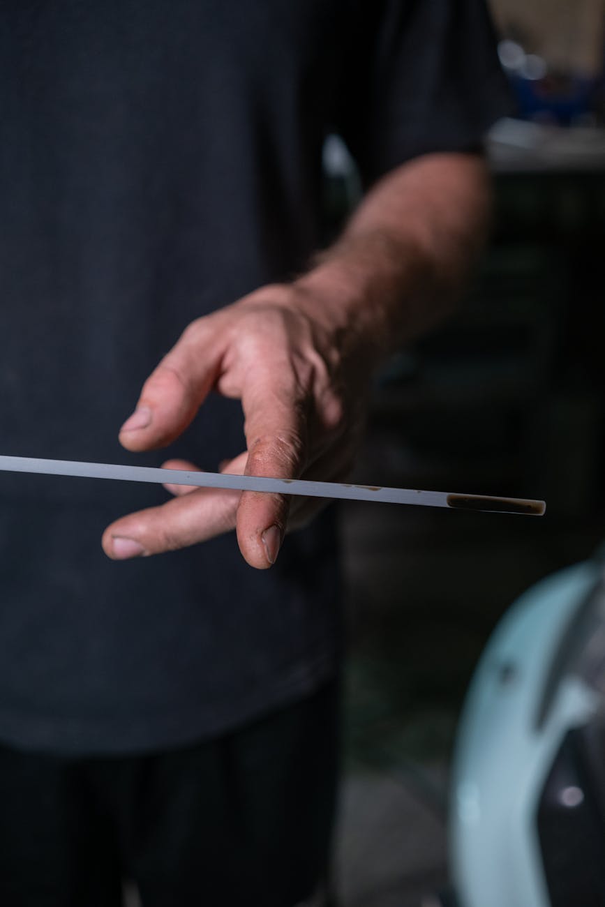 a person holding a dipstick of a car