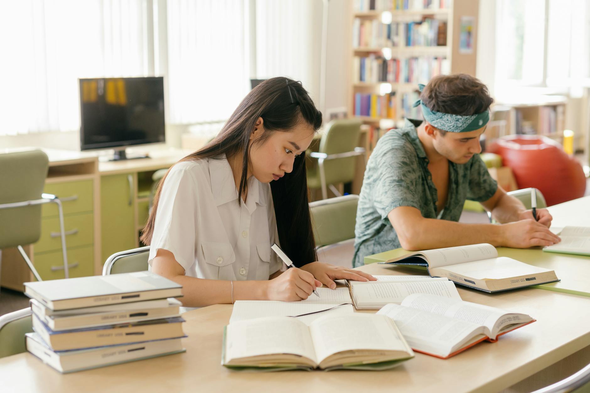 a woman and a man taking notes while reading a book