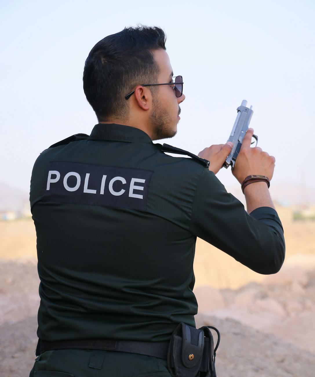 police officer holding gun outdoors during daytime