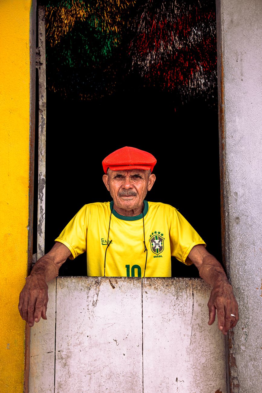 elderly man in yellow shirt standing in window