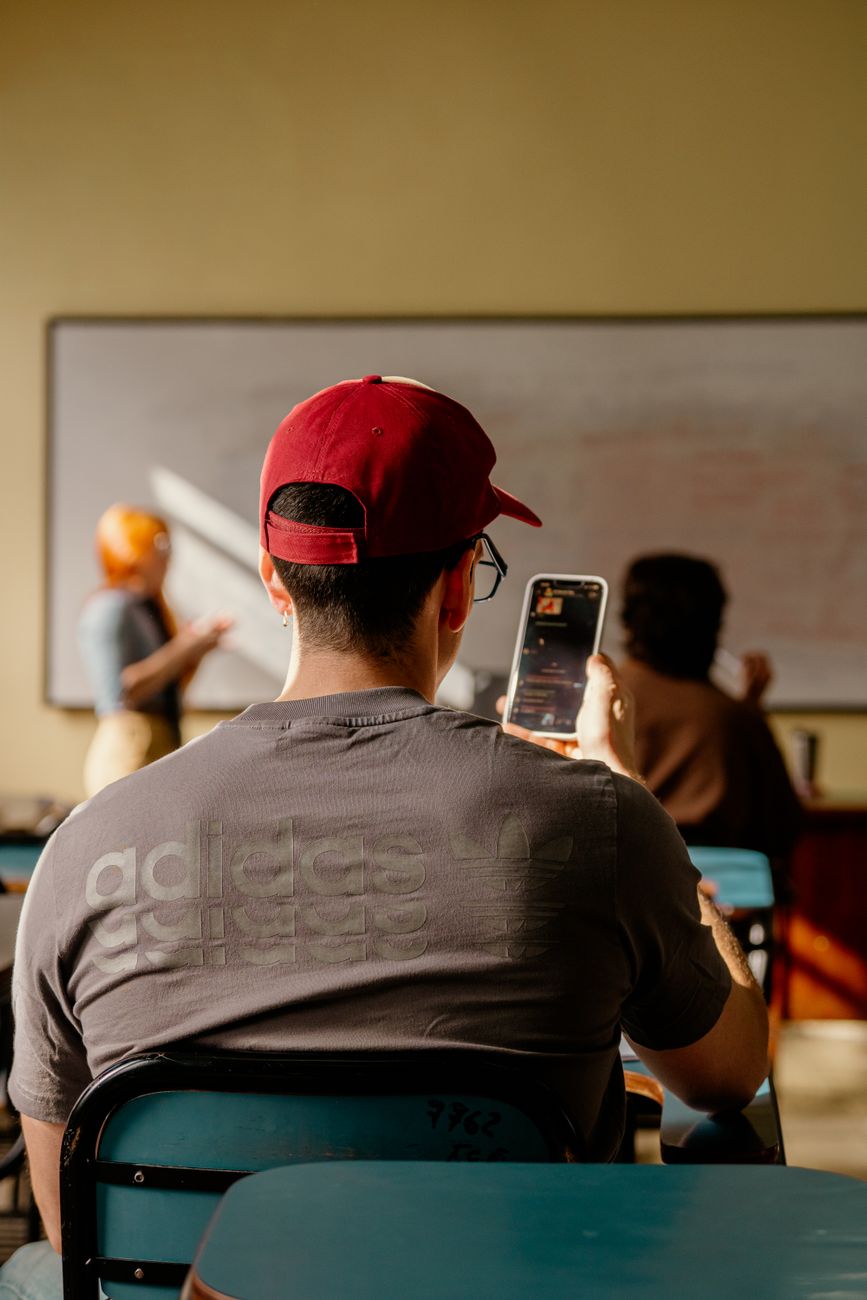 student in classroom with smartphone