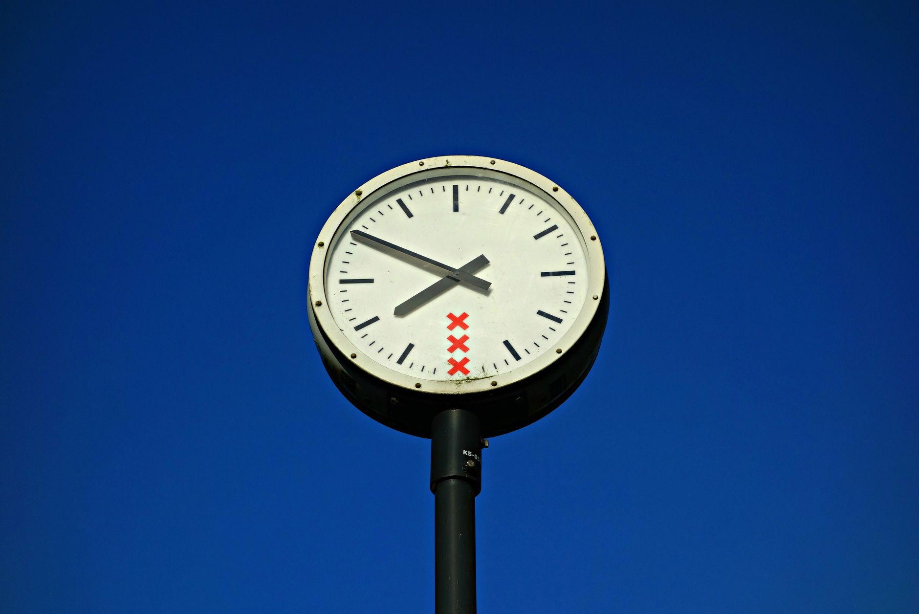 white and black round top analog pedestal clock low angle view