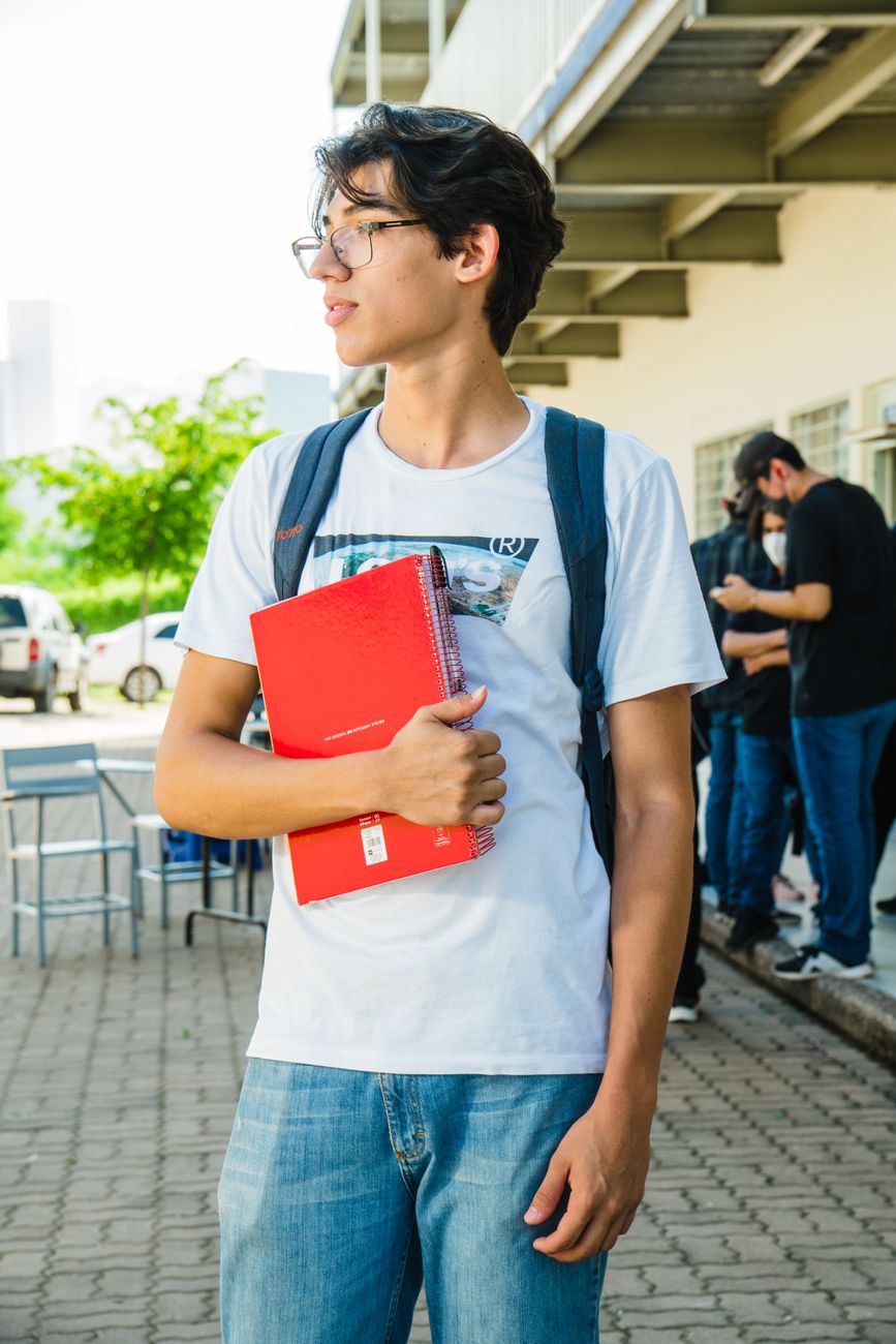 university student holding a notebook outdoors