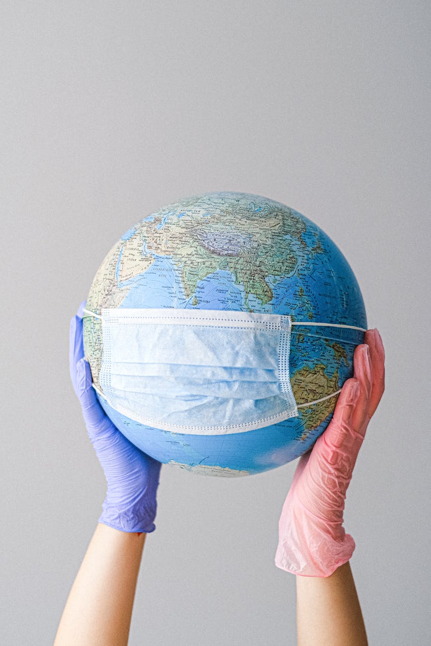 hands with latex gloves holding a globe with a face mask