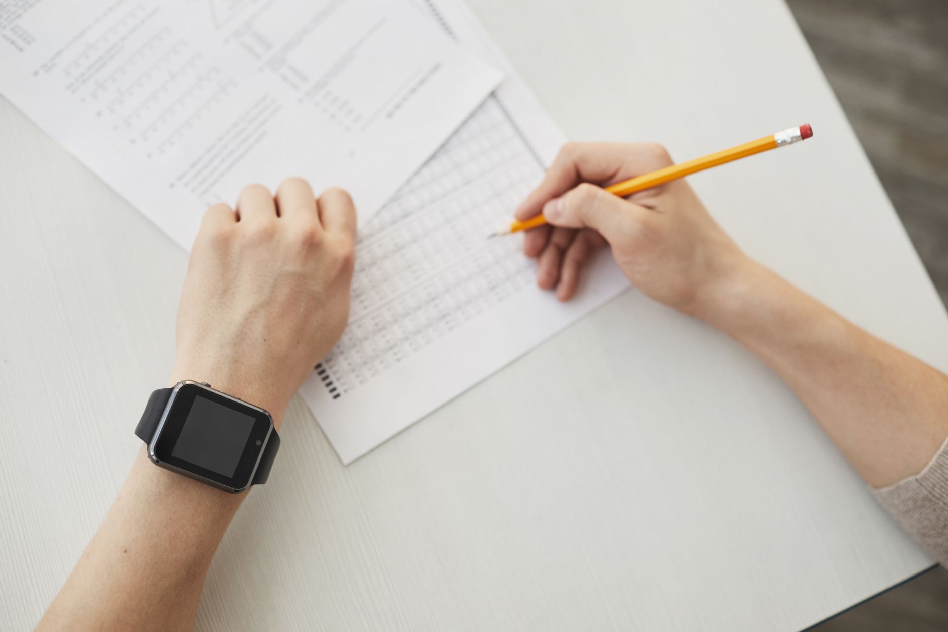 a person wearing a smart watch while holding a pencil