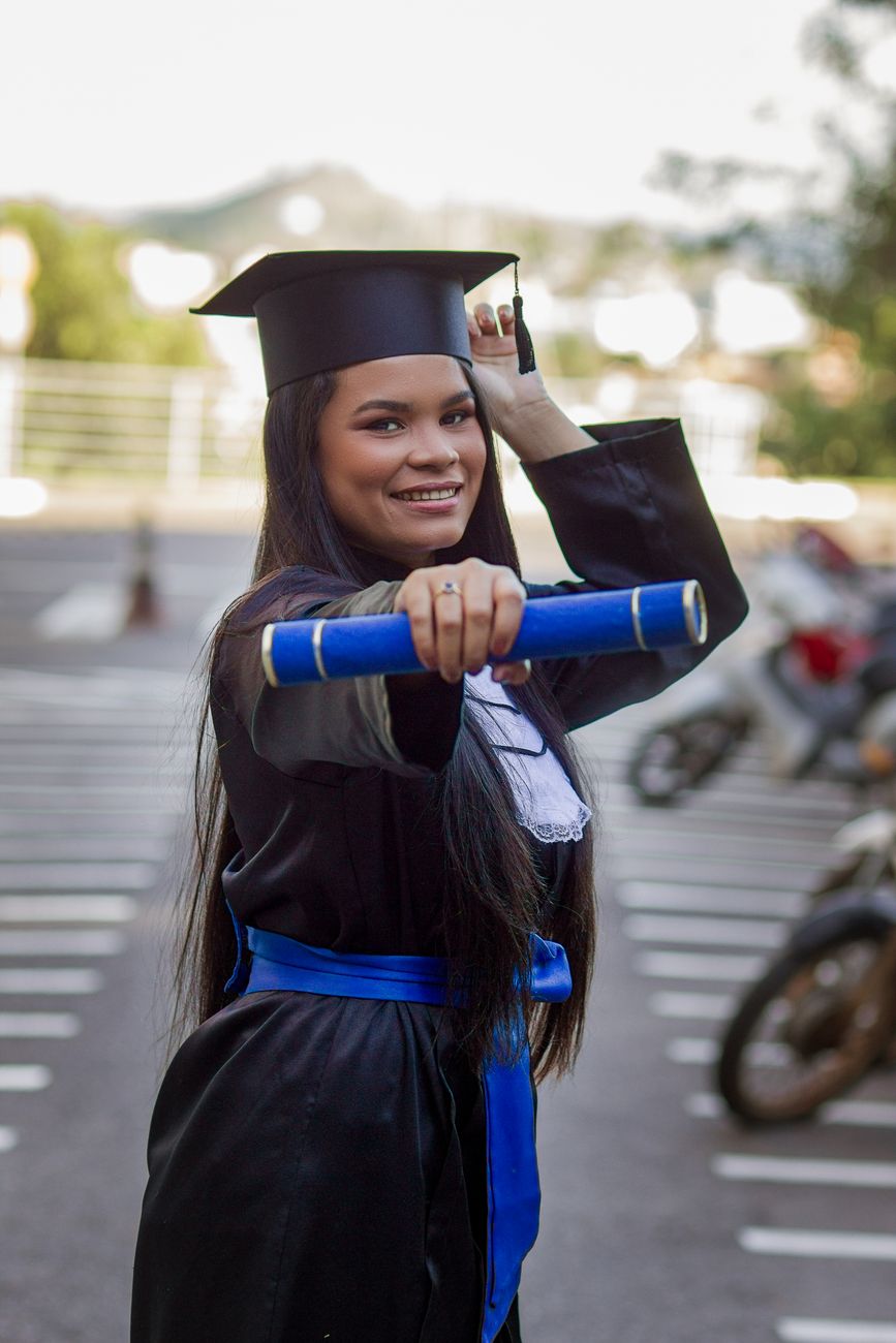 woman posing in graduation clothing on street