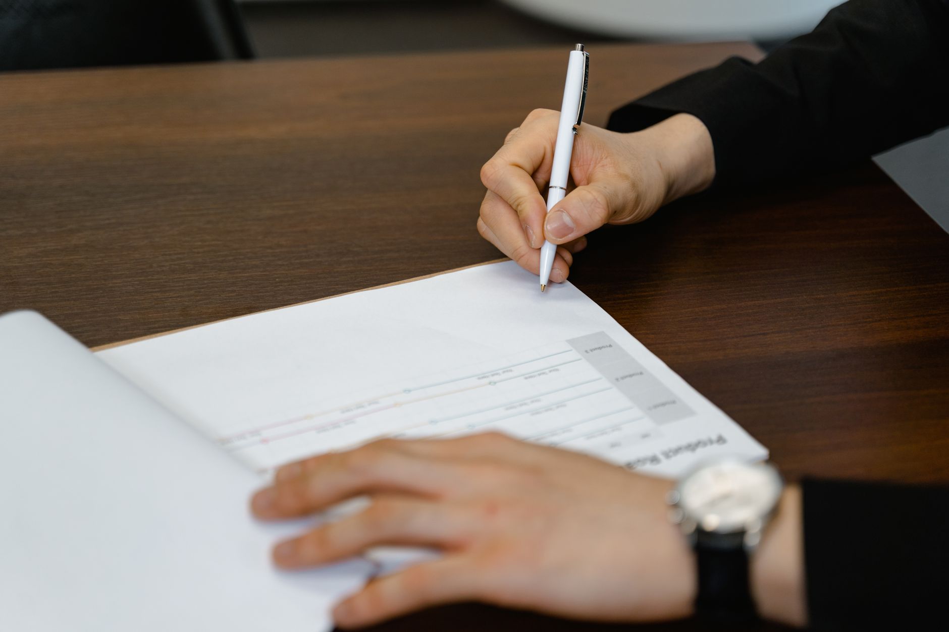 a person writing on paper with a pen