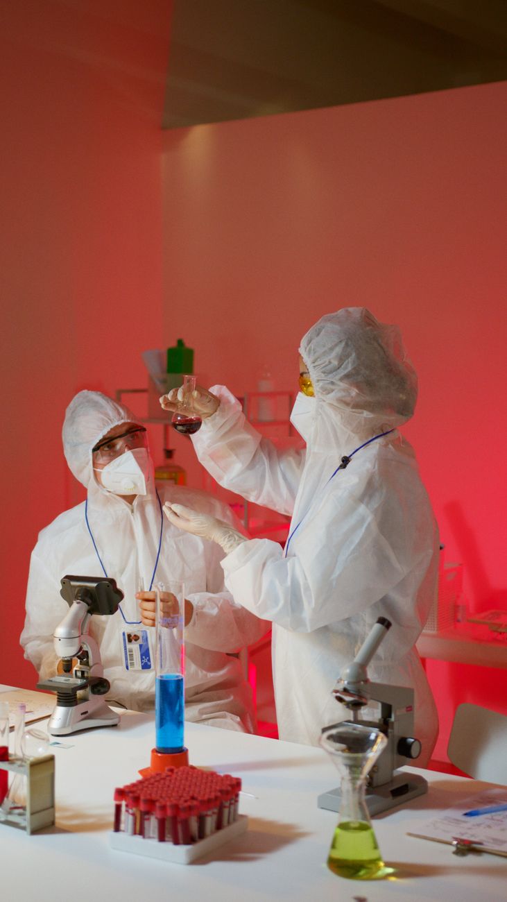 scientists examining chemicals inside a science laboratory using a microscope