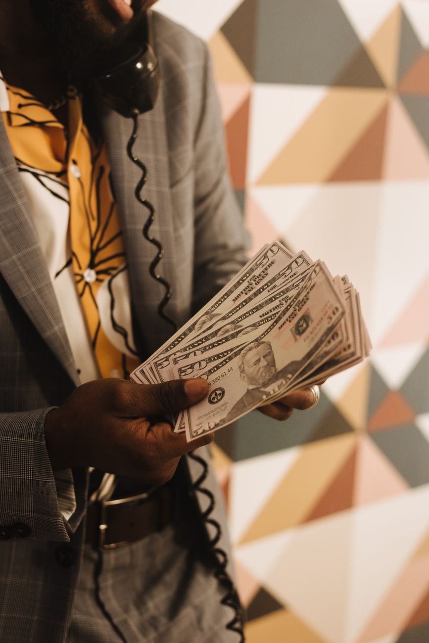 man in gray suit holding dollar bills