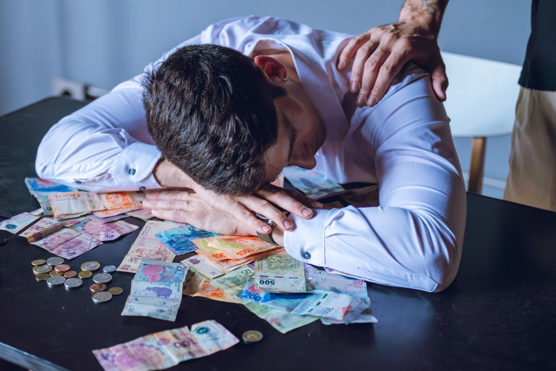 man stressed over argentine currency on table