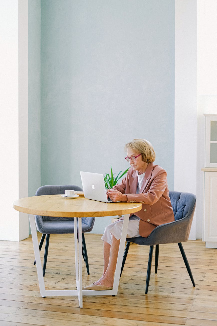 a woman sitting on a chair while using a laptop