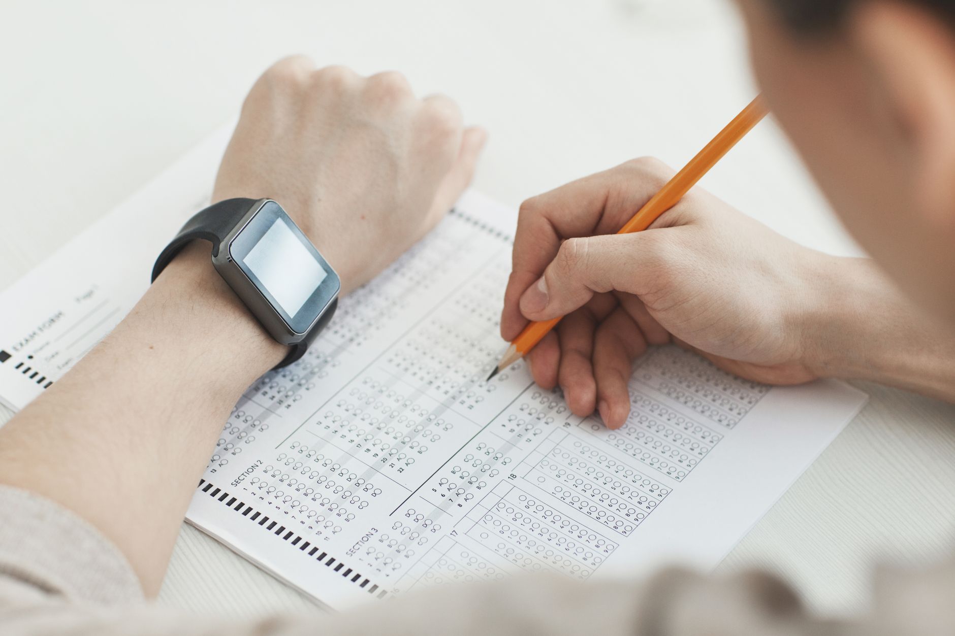 a person writing on white paper using pencil