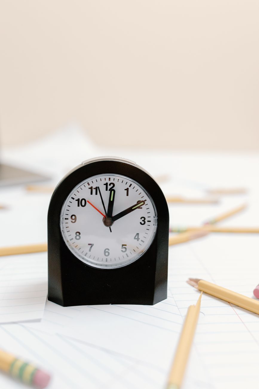 a clock on the white paper with pencils