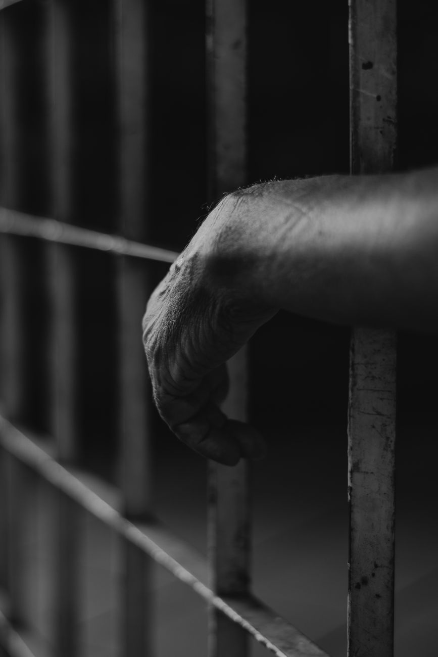 grayscale photo of person s hand on cage