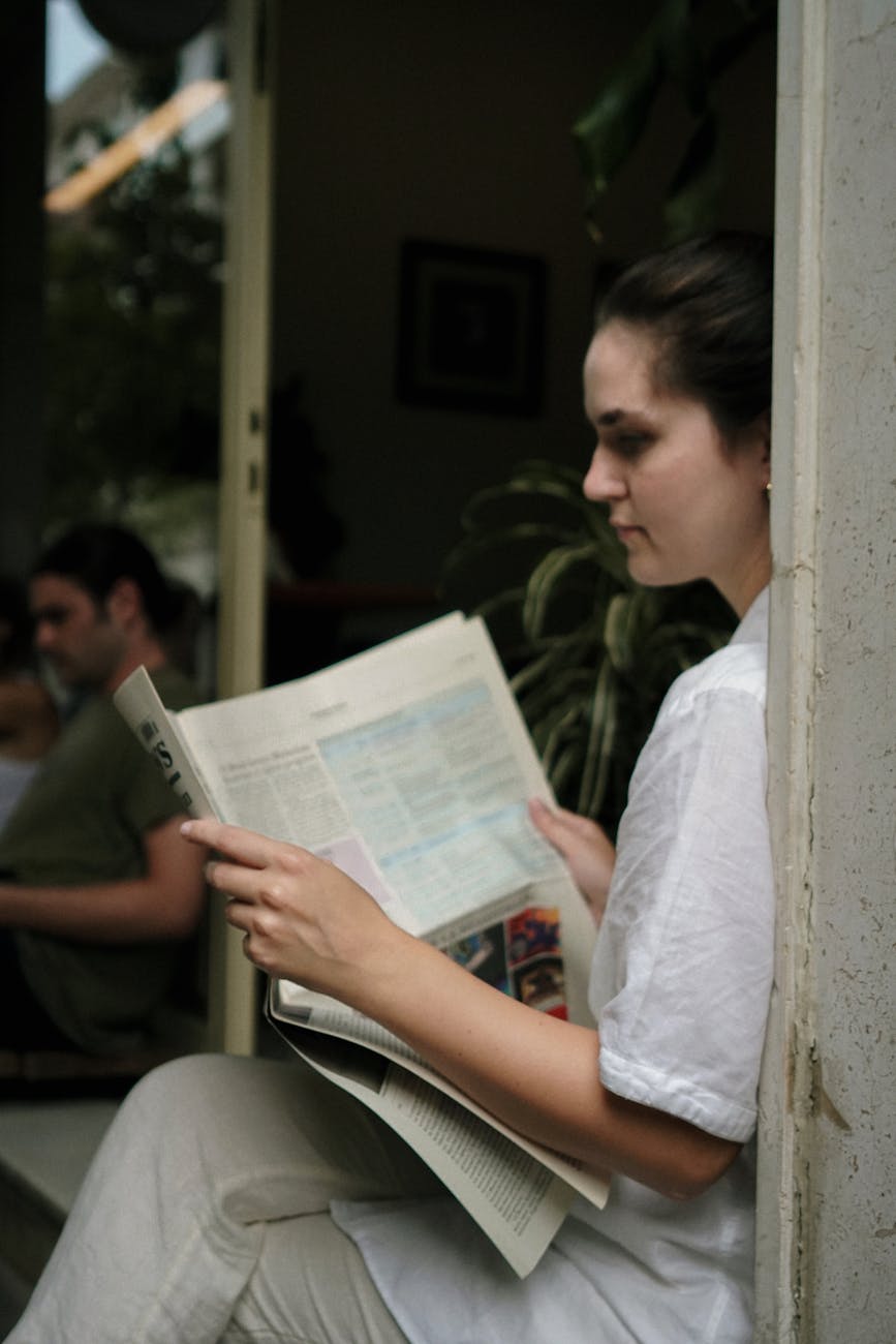 a woman in white shirt reading newspaper
