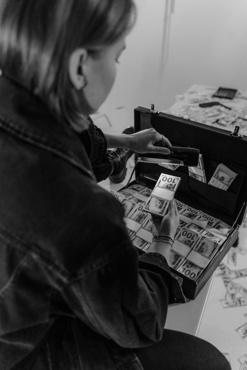 woman using money detector with ultraviolet counterfeit lamp on paper bills